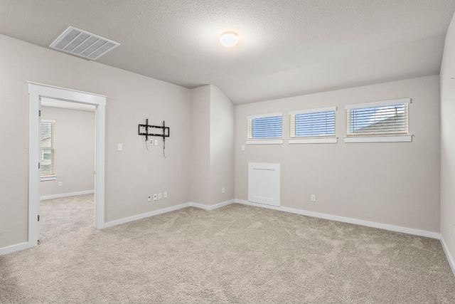 empty room with light carpet and a textured ceiling