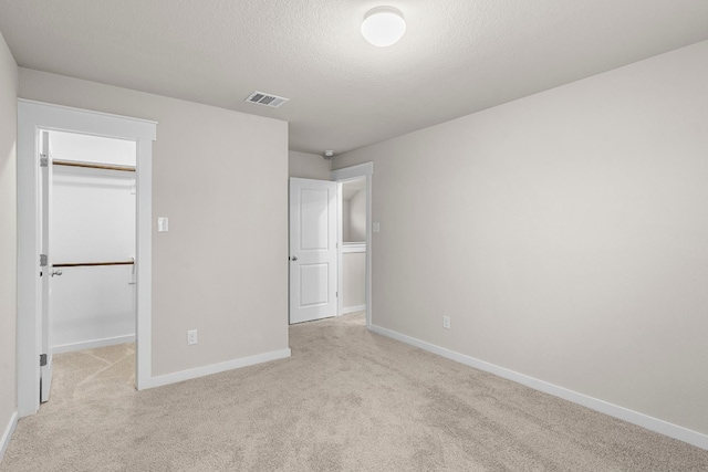 unfurnished bedroom with light carpet, a walk in closet, and a closet