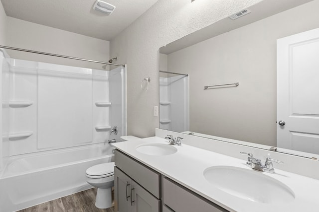 full bathroom with shower / bathing tub combination, hardwood / wood-style floors, a textured ceiling, toilet, and vanity