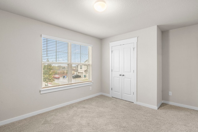 unfurnished bedroom featuring a closet and light colored carpet