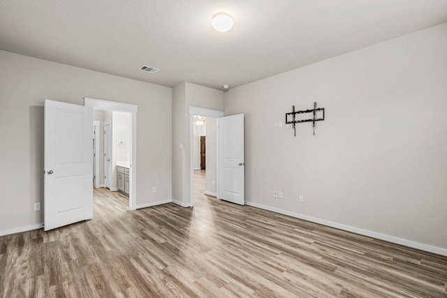 unfurnished bedroom with wood-type flooring and ensuite bathroom