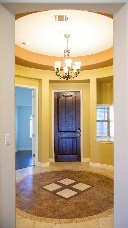 foyer with light tile patterned flooring and an inviting chandelier