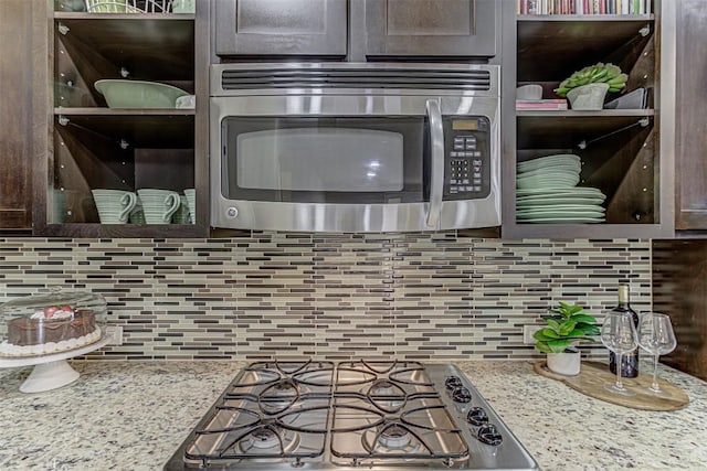 kitchen with decorative backsplash, appliances with stainless steel finishes, light stone countertops, and dark brown cabinets