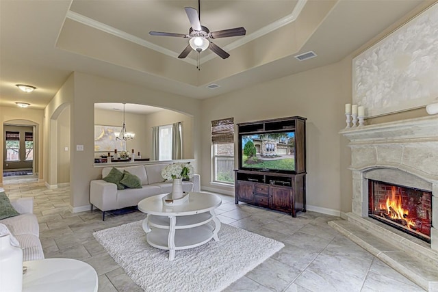 living room featuring a raised ceiling, ceiling fan with notable chandelier, and ornamental molding