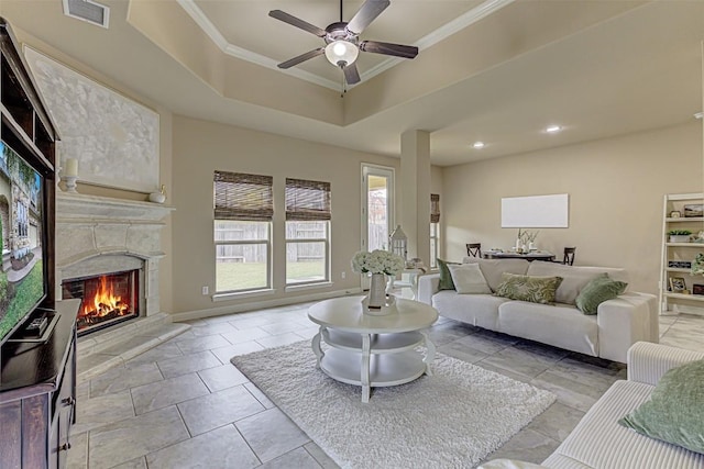 living room with ceiling fan, ornamental molding, light tile patterned floors, and a tray ceiling