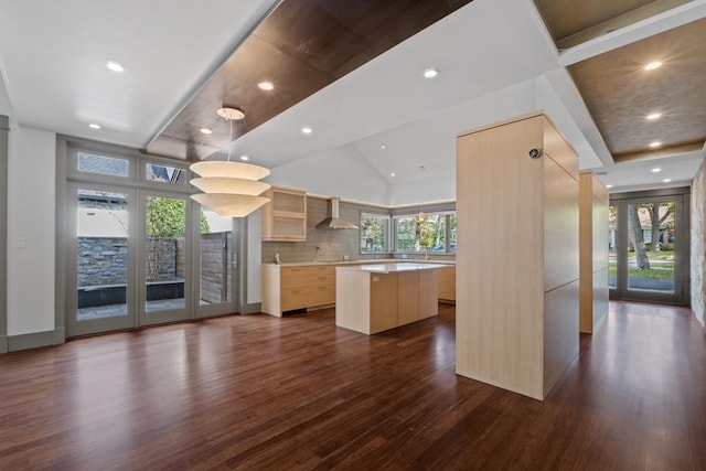 kitchen with plenty of natural light, a center island, wall chimney range hood, and light brown cabinetry