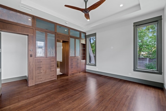 unfurnished bedroom with a raised ceiling, ceiling fan, and dark wood-type flooring