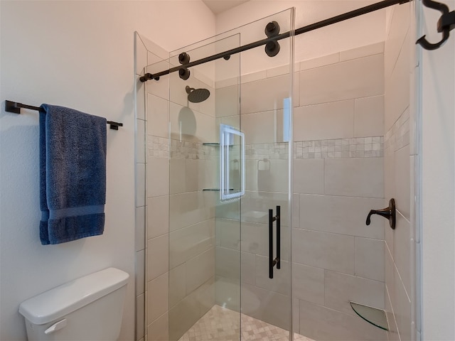 bathroom featuring toilet and a shower with shower door