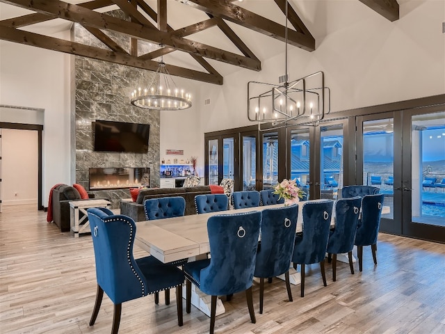 dining area with beam ceiling, a fireplace, high vaulted ceiling, and light wood-type flooring