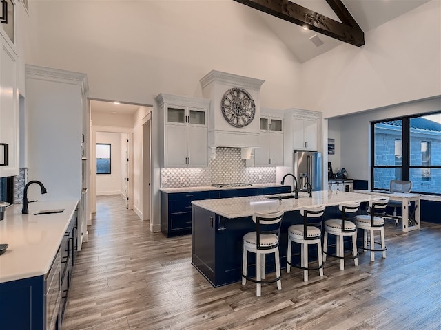 kitchen featuring beamed ceiling, appliances with stainless steel finishes, white cabinets, and sink