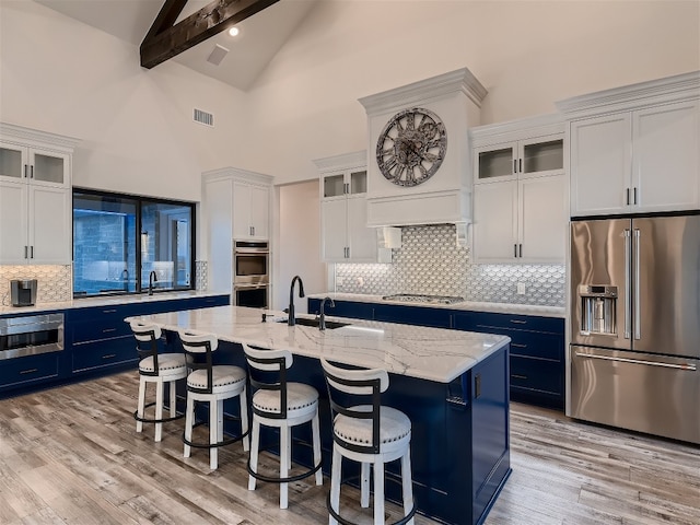 kitchen featuring white cabinets, a kitchen island with sink, beamed ceiling, and appliances with stainless steel finishes