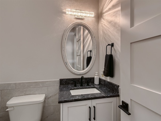 bathroom featuring vanity, toilet, and tile walls