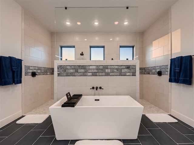 bathroom with tile patterned flooring, a wealth of natural light, and tile walls