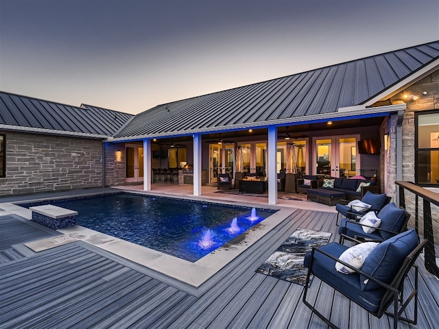 pool at dusk with ceiling fan and an outdoor hangout area