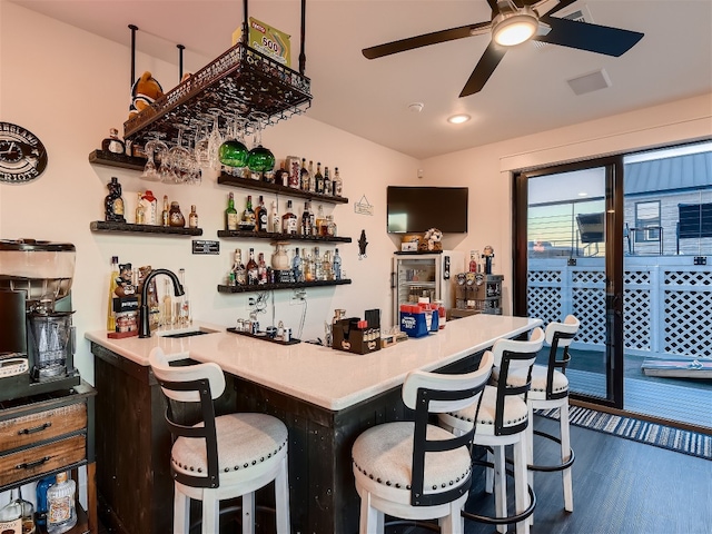 bar with dark hardwood / wood-style flooring, ceiling fan, and sink