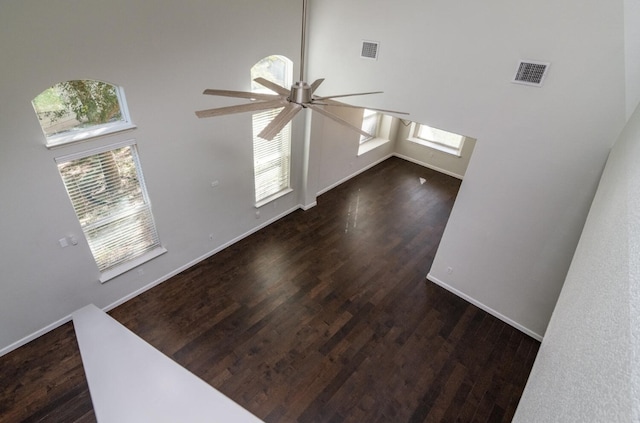 unfurnished living room with ceiling fan, plenty of natural light, and a towering ceiling