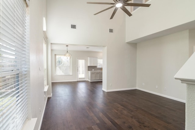 unfurnished living room with a high ceiling, dark hardwood / wood-style flooring, and ceiling fan