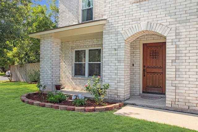 view of exterior entry featuring a lawn