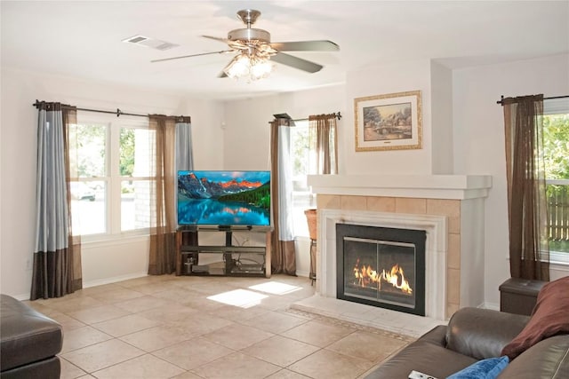 tiled living room featuring ceiling fan and a tiled fireplace