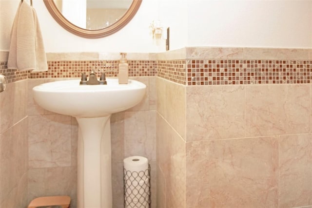 bathroom with decorative backsplash, sink, and tile walls