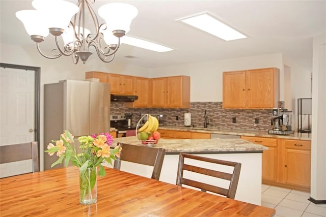 kitchen with a center island, an inviting chandelier, range hood, decorative light fixtures, and stainless steel appliances