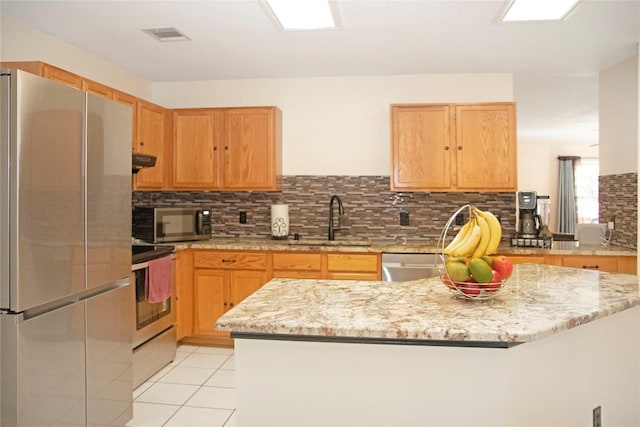 kitchen featuring light stone countertops, sink, stainless steel appliances, tasteful backsplash, and light tile patterned flooring