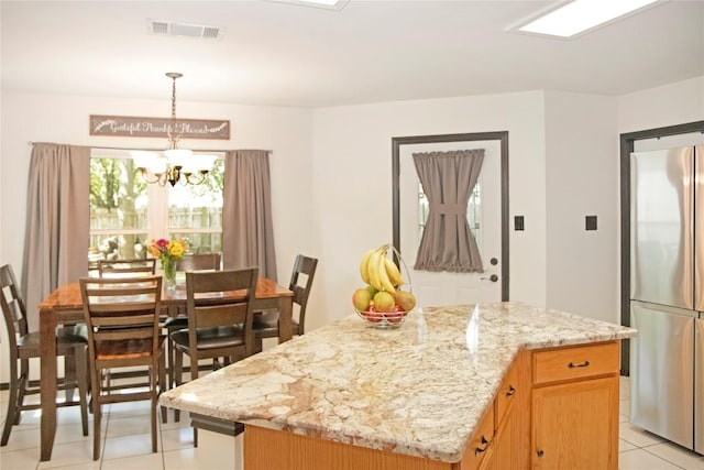 kitchen with a center island, an inviting chandelier, stainless steel fridge, decorative light fixtures, and light tile patterned flooring