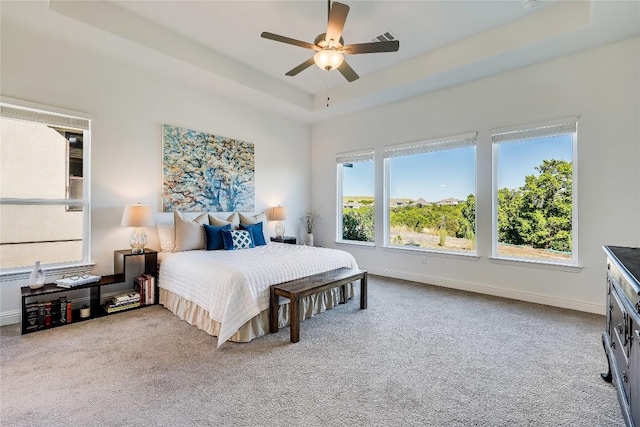 bedroom with light carpet, baseboards, visible vents, ceiling fan, and a tray ceiling