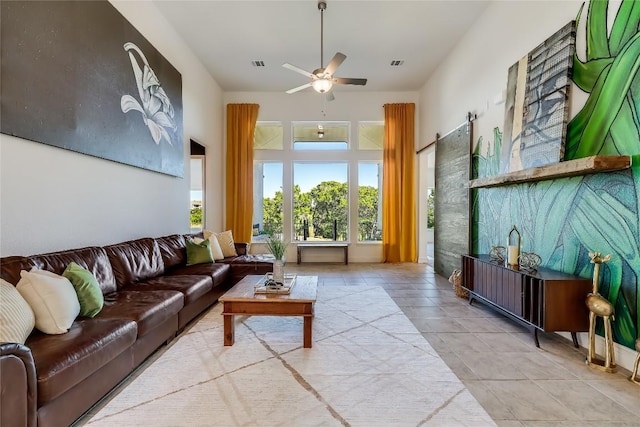 living room with light tile patterned floors, a high ceiling, visible vents, and a ceiling fan