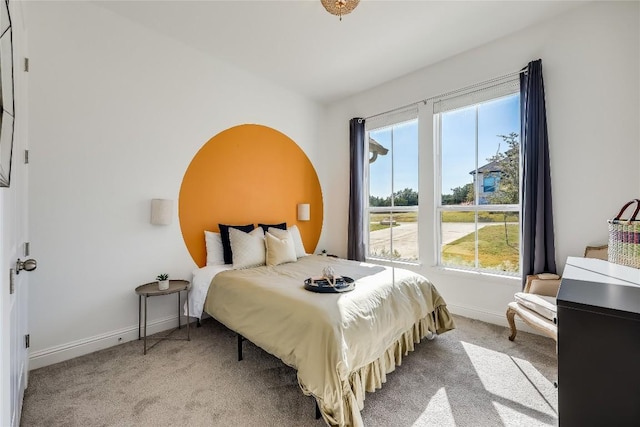 bedroom with light colored carpet, baseboards, and multiple windows