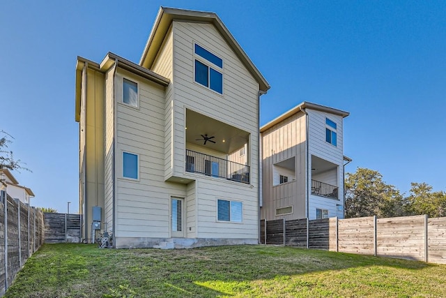 back of house featuring a balcony, a lawn, and ceiling fan