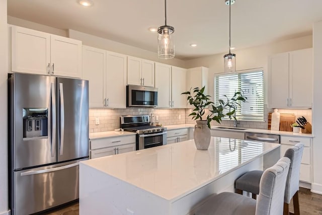 kitchen with decorative light fixtures, white cabinets, a center island, and appliances with stainless steel finishes