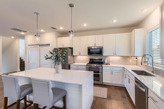 5315 La Crosse Ave Unit 24, Austin, TX 78739 - kitchen featuring appliances with stainless steel finishes, dark wood-type flooring, a kitchen breakfast bar, backsplash, and white cabinets