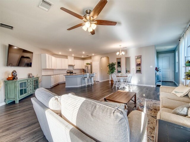 living room with sink, dark wood-type flooring, and ceiling fan with notable chandelier