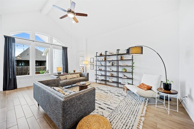 living room featuring ceiling fan, light hardwood / wood-style flooring, beamed ceiling, and high vaulted ceiling