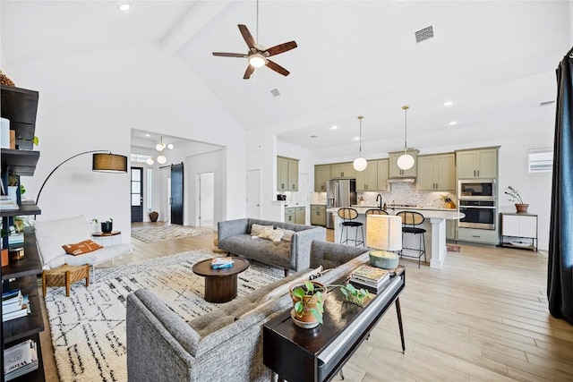 living room with beamed ceiling, light wood-type flooring, ceiling fan with notable chandelier, and high vaulted ceiling