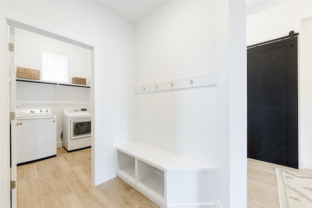 mudroom featuring light wood-type flooring, a barn door, and separate washer and dryer