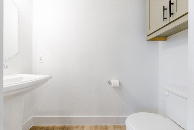 bathroom with hardwood / wood-style flooring, toilet, and sink