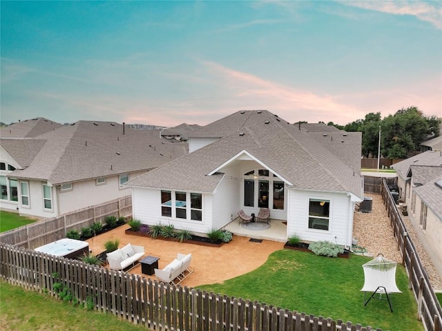 back house at dusk featuring a yard, an outdoor hangout area, and a patio area