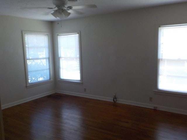 spare room featuring a healthy amount of sunlight and dark hardwood / wood-style flooring