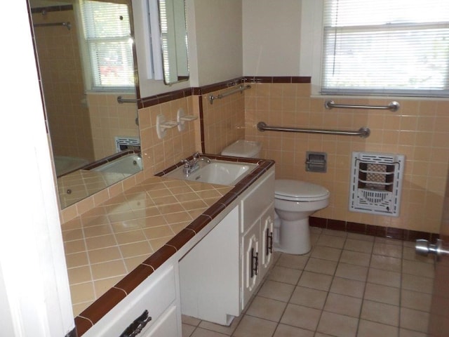 bathroom featuring vanity, tile patterned flooring, toilet, tile walls, and heating unit