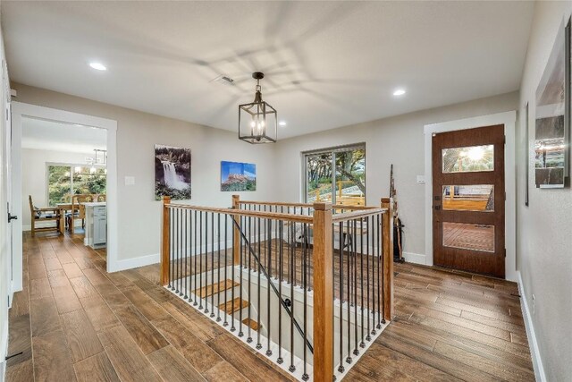 hall with wood-type flooring and an inviting chandelier