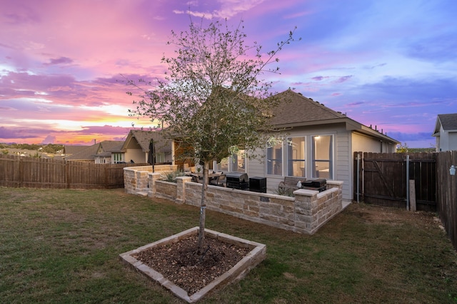 back house at dusk with a patio area and a lawn