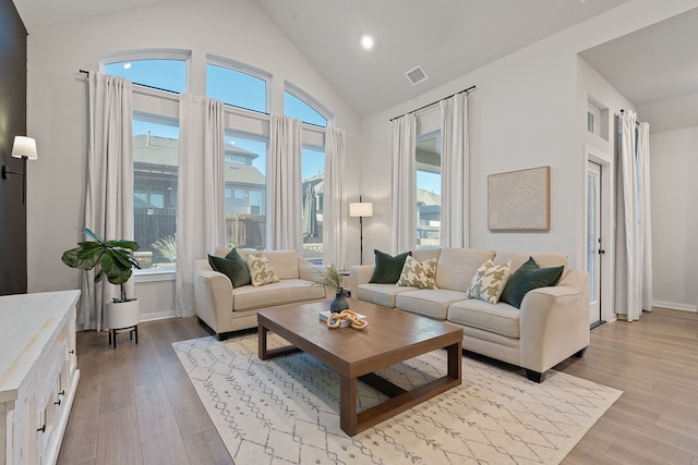 living room with lofted ceiling, a healthy amount of sunlight, and light wood-type flooring