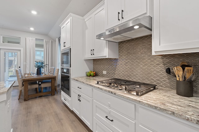 kitchen with light stone counters, white cabinetry, stainless steel appliances, and tasteful backsplash