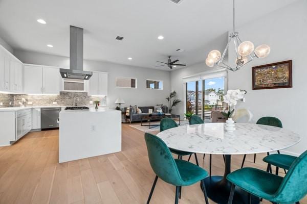 dining room featuring ceiling fan with notable chandelier and light wood-type flooring