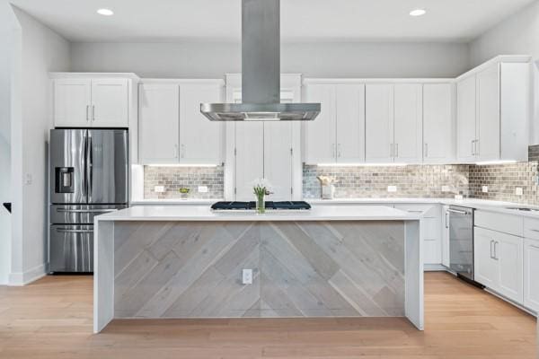 kitchen featuring a center island, white cabinetry, stainless steel appliances, and exhaust hood