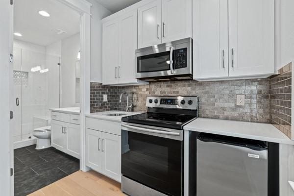 kitchen featuring decorative backsplash, white cabinetry, sink, and appliances with stainless steel finishes