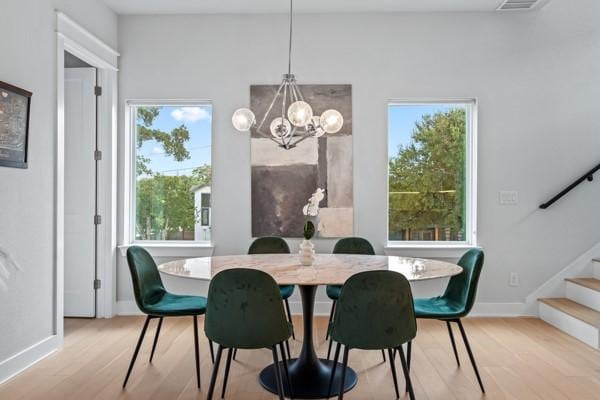 dining space featuring light wood-type flooring, a wealth of natural light, and a notable chandelier