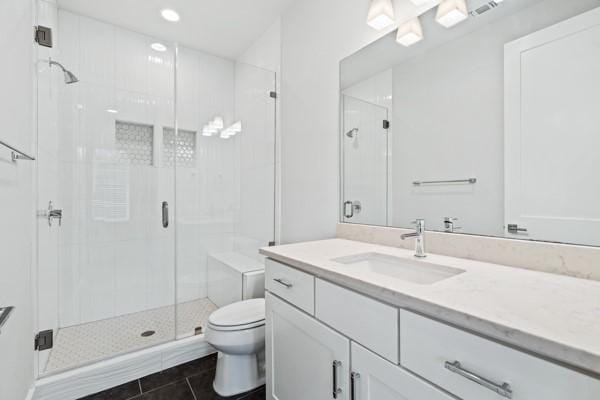 bathroom with tile patterned flooring, vanity, toilet, and a shower with shower door